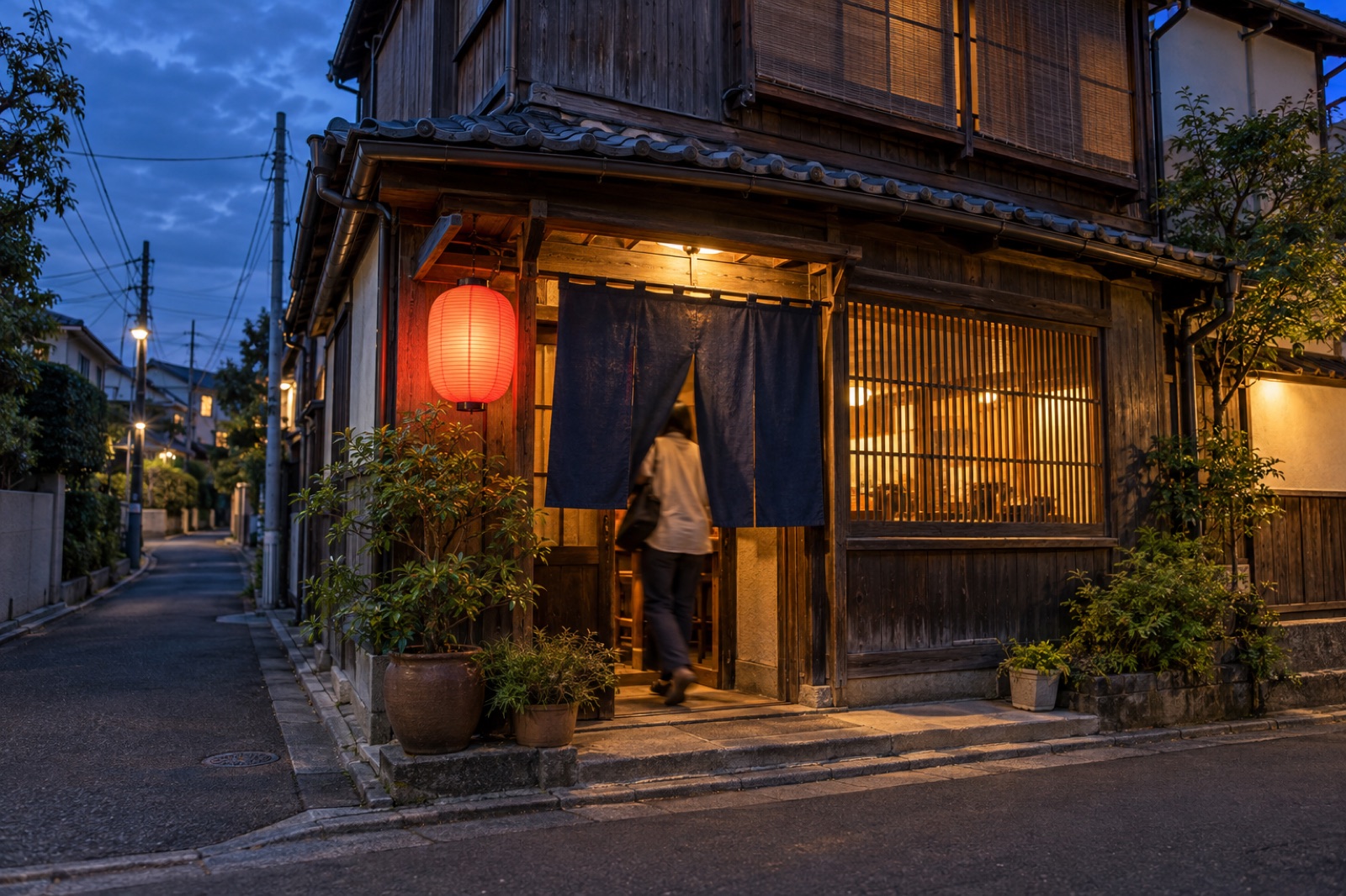 夕暮れの店の外観。暖簾と提灯